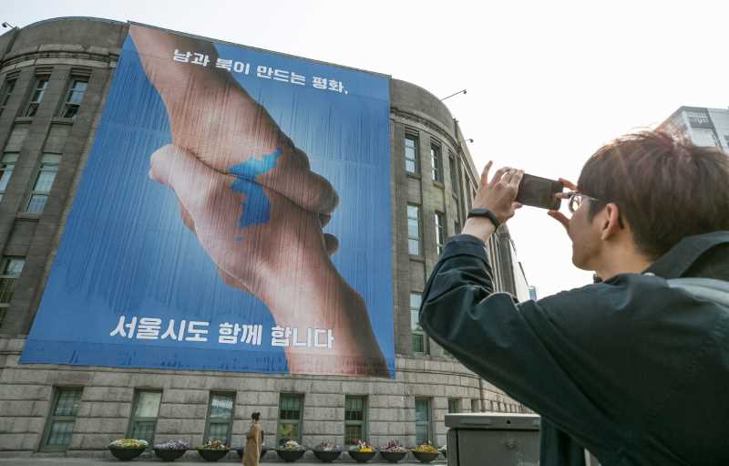Poster showing a handshake and Korean peninsula